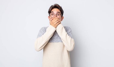 Genç, yakışıklı İspanyol adam elleri ile ağzını kapatıyor, şok olmuş, şaşırmış bir ifadeyle, sır saklıyor ya da 