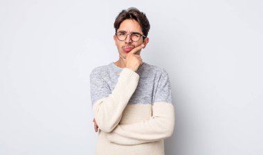 Genç, yakışıklı İspanyol bir adam ciddi, düşünceli ve güvensiz görünüyor, bir kolu çapraz ve çenesi üzerinde, seçenekleri tartıyor.