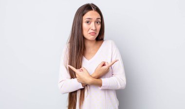 İspanyol güzel kadın şaşkın ve şaşkın görünüyor, güvensiz ve zıt yönlere şüpheyle işaret ediyor.