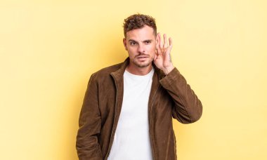 Genç yakışıklı İspanyol adam ciddi ve meraklı görünüyor, dinliyor, gizli bir konuşma veya dedikodu duymaya çalışıyor, kulak misafiri oluyor.