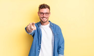 Genç, yakışıklı, İspanyol bir adam kameraya bakıyor. Tatmin olmuş, kendine güvenen, dost canlısı bir gülümsemeyle, seni seçiyor.