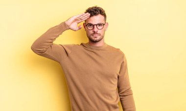 Genç, yakışıklı İspanyol bir adam saygı göstererek, onur ve vatanseverlik adına kameraya selam veriyor.