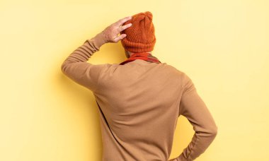 Genç, yakışıklı İspanyol bir adam bilgisiz ve kafası karışık, bir çözüm düşünüyor, eli kalçasında, diğeri de kafasında, dikiz aynasından.