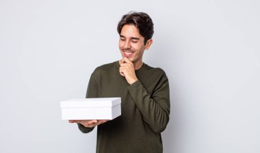 Mutlu, kendinden emin, elleri çenesinde gülümseyen genç bir İspanyol. beyaz kutu kavramı