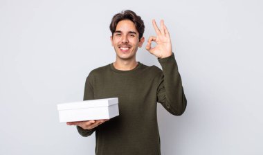 Genç İspanyol adam kendini mutlu hissediyor, iyi bir jestle onaylıyor. beyaz kutu kavramı
