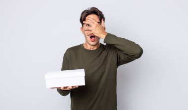 Genç İspanyol bir adam şok olmuş, korkmuş ya da korkmuş görünüyor. Yüzü elle kapatılmış. beyaz kutu kavramı