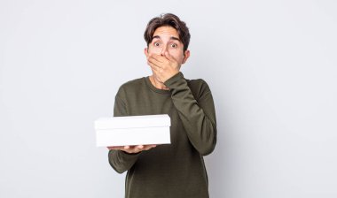 Genç İspanyol adam şok olmuş bir şekilde ağzını eliyle kapatıyor. beyaz kutu kavramı