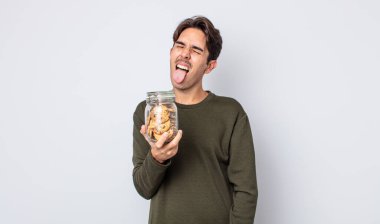 Neşeli ve asi tavırlı, şaka yapan ve dilini dışarı çıkaran genç İspanyol bir adam. kurabiye konsepti