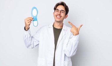 Genç İspanyol adam kendine güvenerek gülümsüyor ve kendi gülüşünü gösteriyor. Kayropodist konsepti