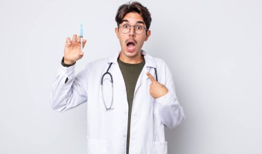 Genç İspanyol bir adam şok olmuş ve ağzı açık, kendini işaret ederek şaşırmış görünüyor. doktor şırınga konsepti