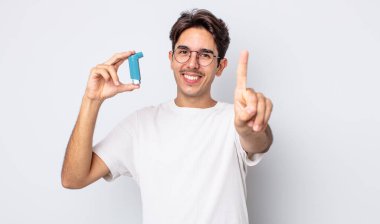 Genç İspanyol adam gururla gülümsüyor ve kendinden emin bir numara oluyor. astım konsepti