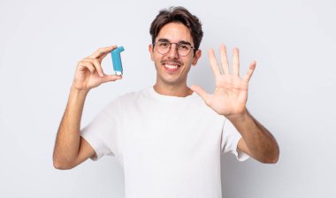 Genç İspanyol adam gülümsüyor ve arkadaş canlısı görünüyor, beş numarayı gösteriyor. astım konsepti