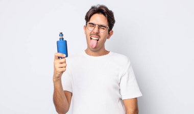 Neşeli ve asi tavırlı, şaka yapan ve dilini dışarı çıkaran genç İspanyol bir adam. duman buharlaştırıcı kavramı