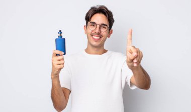 Genç İspanyol adam gülümsüyor ve arkadaş canlısı görünüyor, bir numarayı gösteriyor. duman buharlaştırıcı kavramı