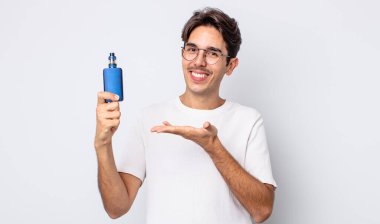 Genç İspanyol adam neşeyle gülümsüyor, mutlu hissediyor ve bir konsept gösteriyor. duman buharlaştırıcı kavramı