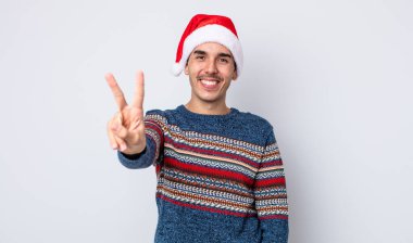 Genç İspanyol adam gülümsüyor ve mutlu görünüyor, zafer ya da barış işareti yapıyor. Yeni yıl ve Noel konsepti