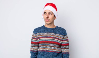 Genç İspanyol bir adam üzgün, üzgün ya da kızgın hissediyor ve yan tarafa bakıyor. Yeni yıl ve Noel konsepti