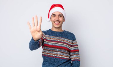 Genç İspanyol adam gülümsüyor ve arkadaş canlısı görünüyor, dört numarayı gösteriyor. Yeni yıl ve Noel konsepti