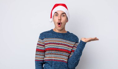 Genç İspanyol bir adam şaşırmış ve şok olmuş görünüyor. Çenesi düşmüş ve elinde bir nesne tutuyor. Yeni yıl ve Noel konsepti