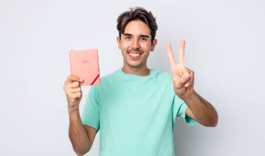 Genç İspanyol adam gülümsüyor ve arkadaş canlısı görünüyor, iki numarayı gösteriyor. 2022 planlayıcı kavramı