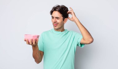 Genç İspanyol adam şaşkın ve kafası karışık, kaşınan bir kafa hissediyor. boş kase kavramı