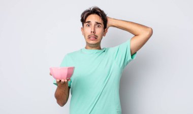 Genç İspanyol bir adam stresli, endişeli ya da korkmuş hissediyor, elleri başının üstünde. boş kase kavramı