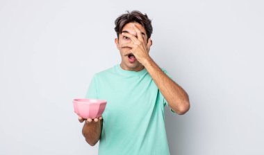 Genç İspanyol bir adam şok olmuş, korkmuş ya da korkmuş görünüyor. Yüzü elle kapatılmış. boş kase kavramı