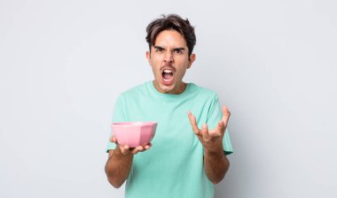 Genç İspanyol adam sinirli, sinirli ve sinirli görünüyor. boş kase kavramı