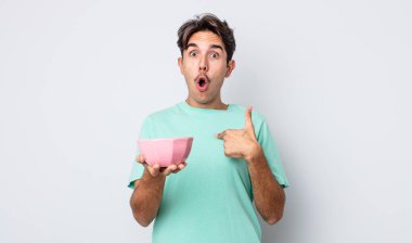 Genç İspanyol bir adam şok olmuş ve ağzı açık, kendini işaret ederek şaşırmış görünüyor. boş kase kavramı