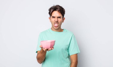 Genç İspanyol adam iğreniyor, sinirleniyor ve dili dışarı çıkıyor. boş kase kavramı