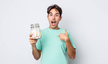 Genç İspanyol bir adam mutlu hissediyor ve heyecanla kendini işaret ediyor. jöle şekeri konsepti