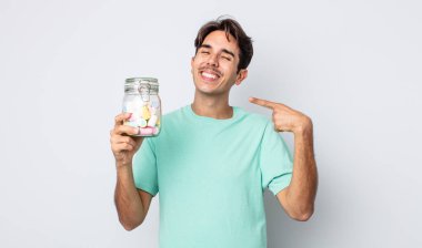 Genç İspanyol adam kendine güvenerek gülümsüyor ve kendi gülüşünü gösteriyor. jöle şekeri konsepti