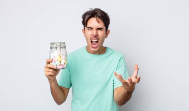 Genç İspanyol adam sinirli, sinirli ve sinirli görünüyor. jöle şekeri konsepti