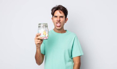 Genç İspanyol adam iğreniyor, sinirleniyor ve dili dışarı çıkıyor. jöle şekeri konsepti