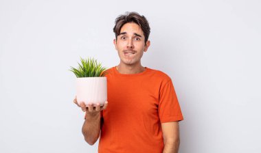 Genç İspanyol adam şaşkın ve şaşkın görünüyor. dekoratif bitki konsepti
