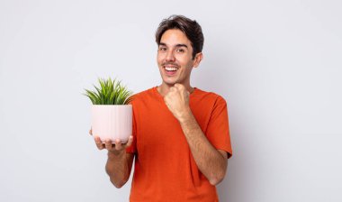 Genç İspanyol adam kendini mutlu hissediyor ve bir meydan okumayla yüzleşiyor ya da kutluyor. dekoratif bitki konsepti