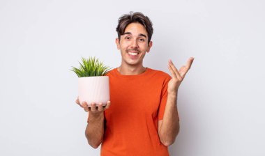 Genç İspanyol adam mutlu hissediyor, bir çözüm ya da fikir bulduğuna şaşırıyor. dekoratif bitki konsepti