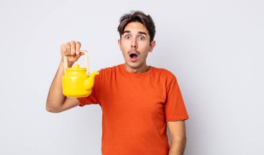 Genç İspanyol adam çok şaşırmış ya da şaşkın görünüyor. çaydanlık konsepti