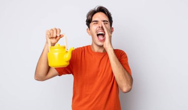 Genç İspanyol adam kendini mutlu hissediyor, elleri ağızının yanında bağırarak bağırıyor. çaydanlık konsepti