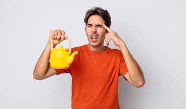 Genç İspanyol adam şaşkın ve şaşkın hissediyor, senin deli olduğunu gösteriyor. çaydanlık konsepti