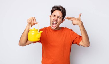 Genç İspanyol adam mutsuz ve stresli görünüyor, intihar jesti silah işareti yapıyor. çaydanlık konsepti