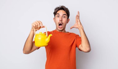 Genç İspanyol adam ellerini havaya kaldırarak çığlık atıyor. çaydanlık konsepti