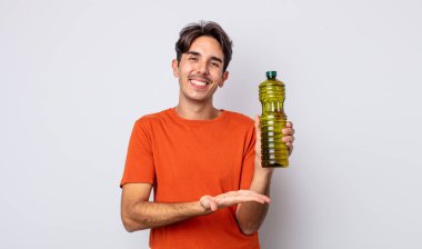 Genç İspanyol adam neşeyle gülümsüyor, mutlu hissediyor ve bir konsept gösteriyor. Zeytin yağı kavramı