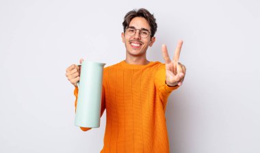Genç İspanyol adam gülümsüyor ve mutlu görünüyor, zafer ya da barış işareti yapıyor. termos kavramı