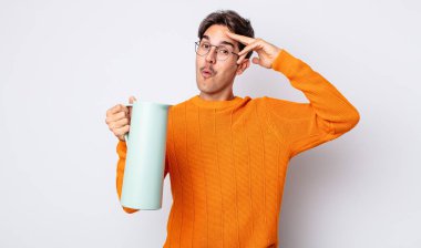 Genç İspanyol adam mutlu, şaşkın ve şaşırmış görünüyor. termos kavramı