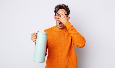 Genç İspanyol bir adam şok olmuş, korkmuş ya da korkmuş görünüyor. Yüzü elle kapatılmış. termos kavramı