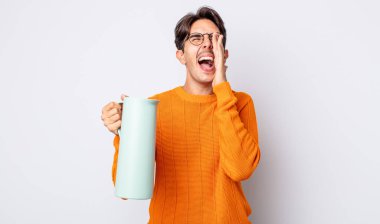 Genç İspanyol adam kendini mutlu hissediyor, elleri ağızının yanında bağırarak bağırıyor. termos kavramı