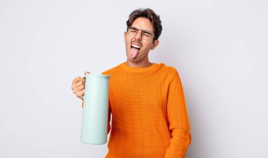 Neşeli ve asi tavırlı, şaka yapan ve dilini dışarı çıkaran genç İspanyol bir adam. termos kavramı