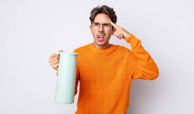 Genç İspanyol adam şaşkın ve şaşkın hissediyor, senin deli olduğunu gösteriyor. termos kavramı