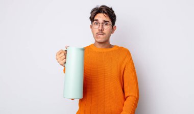 Genç İspanyol adam şaşkın ve şaşkın görünüyor. termos kavramı